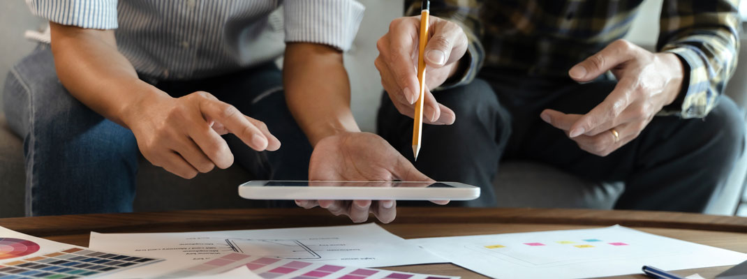 Two people looking at, and pointing at, an iPad.